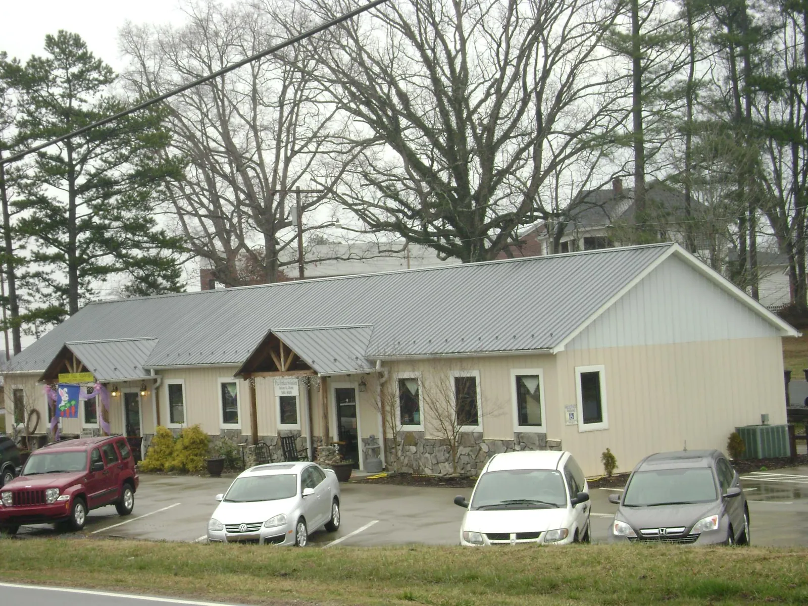 Gray metal roof with timber entry brackets on a small commercial building in Sparta
